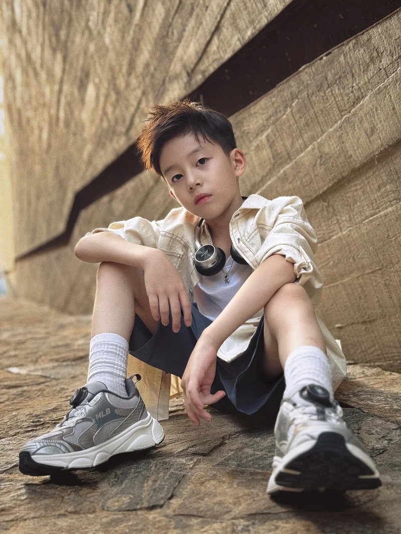 Bé trai 10 tuổi ngồi trên bậc thềm, ánh mắt dịu dàng