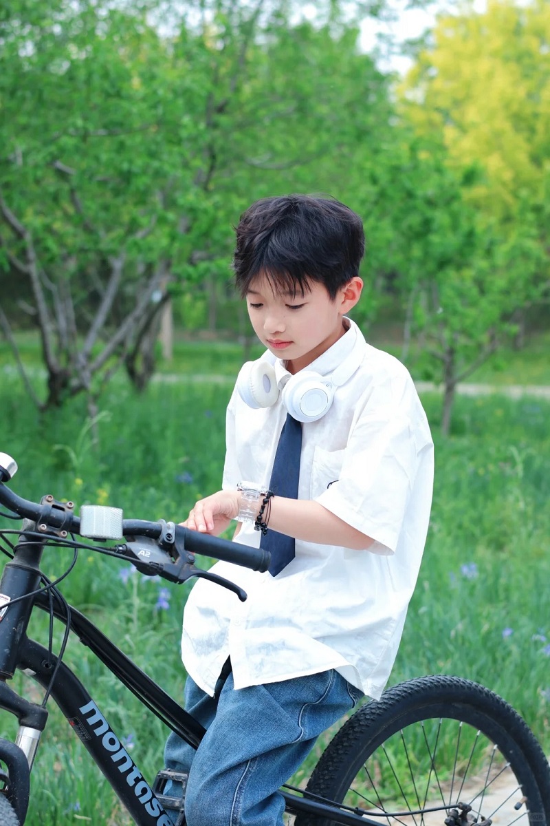 Bé trai 10 tuổi đứng giữa đồng cỏ xanh rì