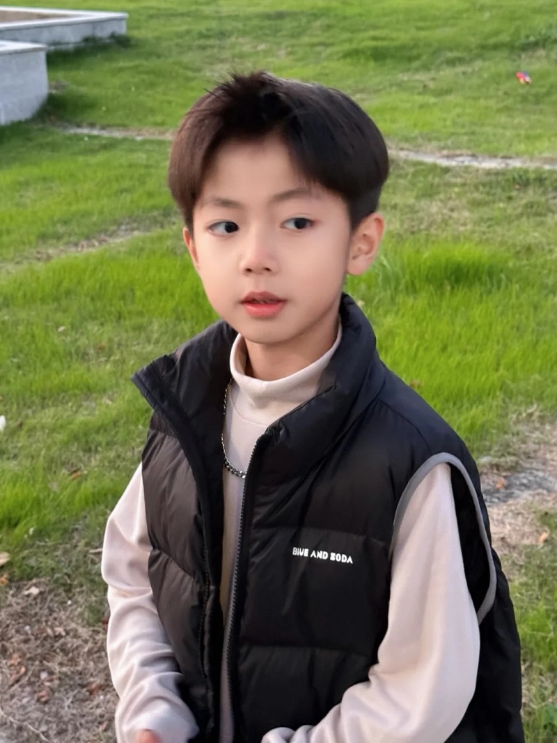 Hình ảnh trai đẹp 10 tuổi đứng giữa công viên xanh mát