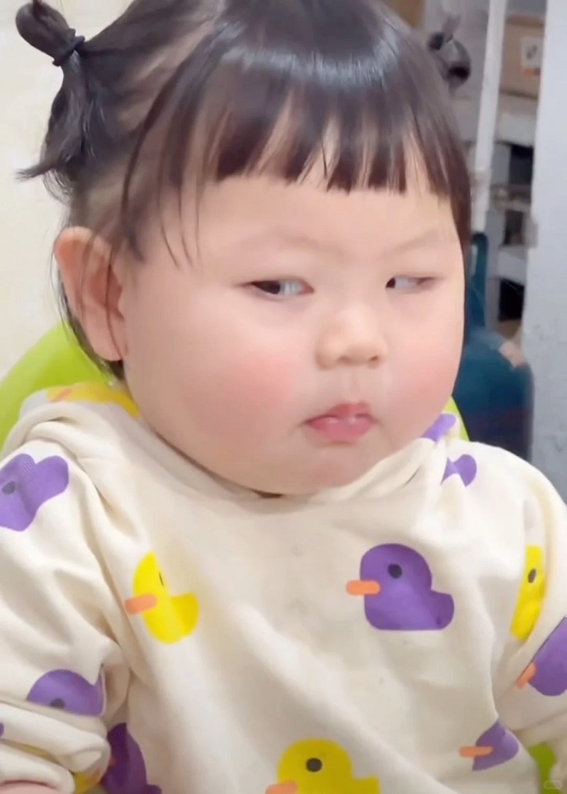 Meme nghi ngờ Bé gái mặt đơ nhìn sang một bên với biểu cảm “nghi lắm nha”.